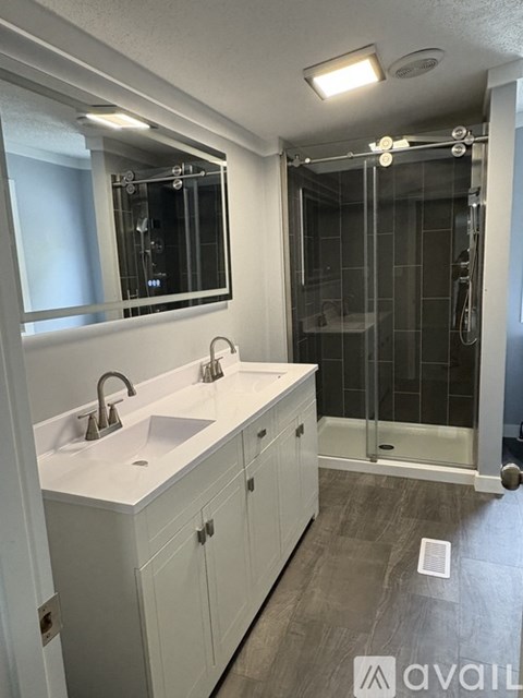 A bathroom with a white sink and a glass shower stall.