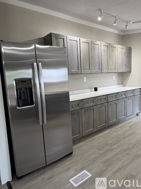 A stainless steel refrigerator in a kitchen with wooden cabinets.