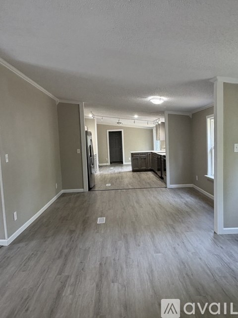 A spacious room with light grey walls and a wooden floor.