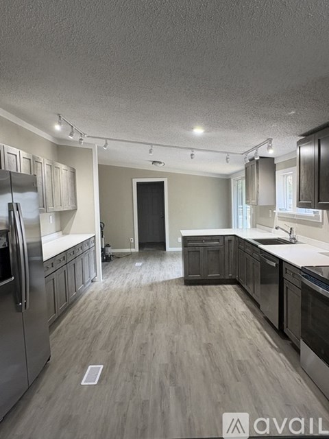A kitchen with a refrigerator, sink, and cabinets.