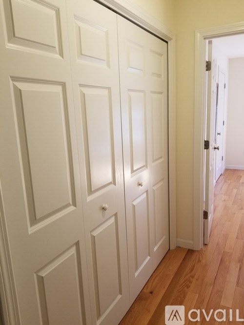 A white door with a handle is in a room with wooden floors.