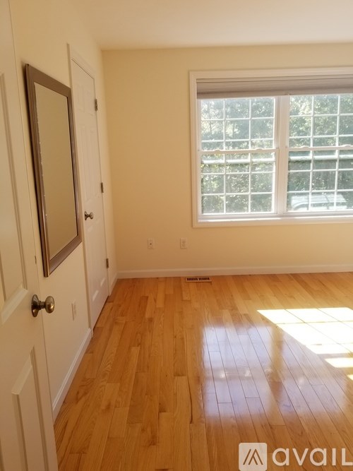 A room with a wooden floor and a window with blinds.