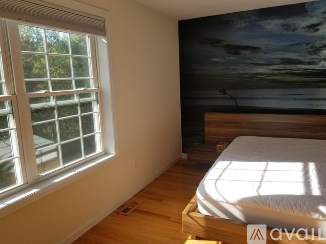 A bedroom with a bed, a window, and a wall mural.