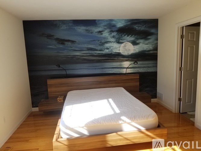A bedroom with a bed and a wall mural of a beach scene.