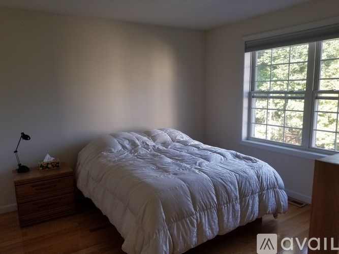 A bedroom with a large bed and a window letting in natural light.