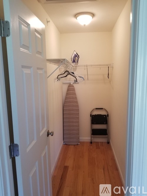 A hallway with a white door and a clothes rack.
