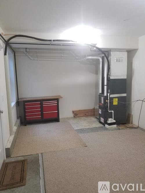 A room with a wall-mounted air conditioner unit and a red tool chest.