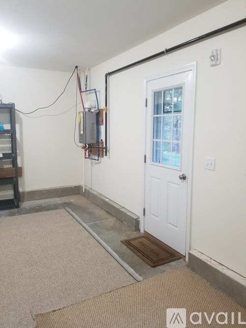 A room with a door, carpet, and a wall-mounted electrical panel.