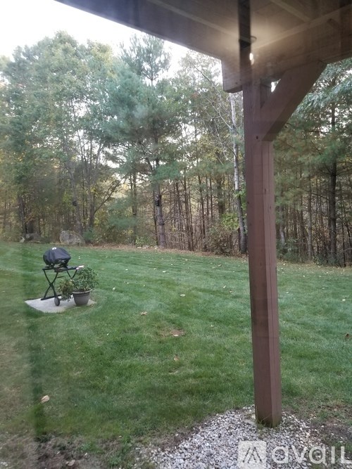 A patio with a chair and table is seen from a window.