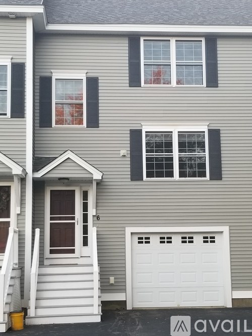 A grey house with a white garage door and a window with black shutters.