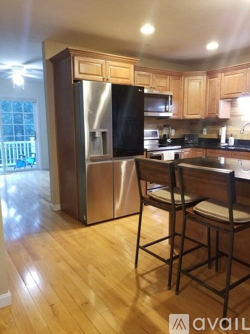 A kitchen with wooden floors and a black fridge.