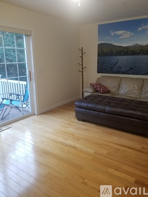 A living room with a couch and a painting of a lake.