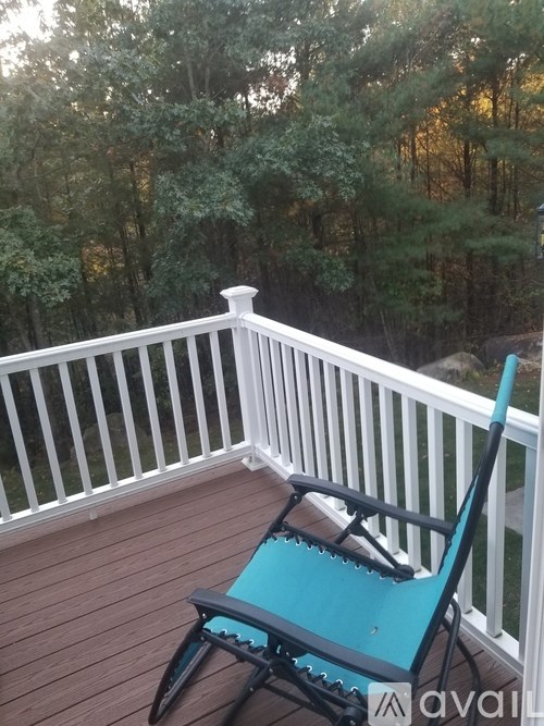 A blue chair sits on a wooden deck with a white railing.