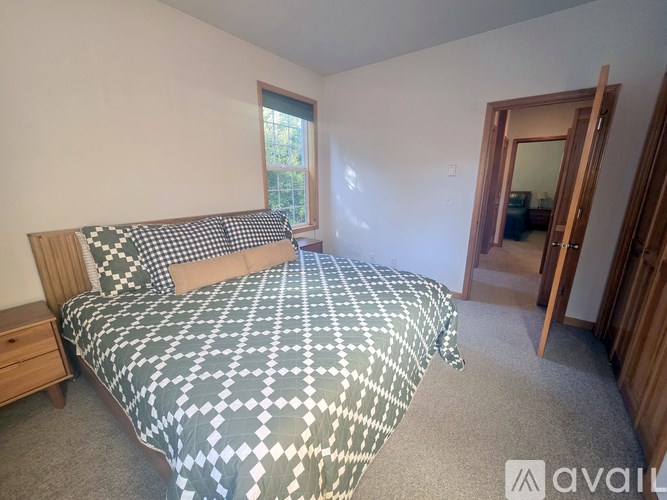 A bedroom with a bed, nightstand, and window.