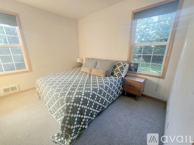 A bedroom with a bed, nightstand, and window.