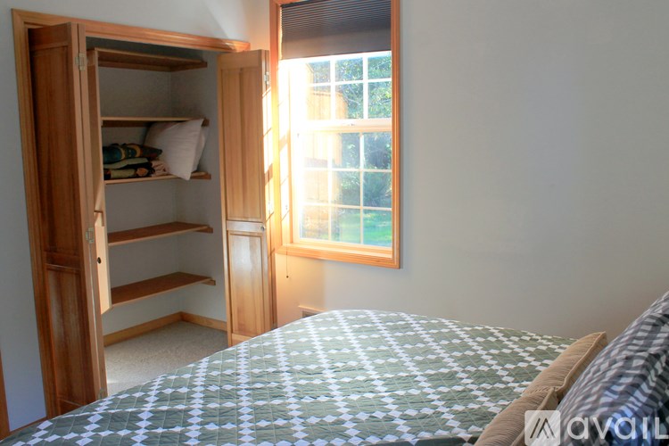 A bedroom with a bed and a wardrobe with an open door.