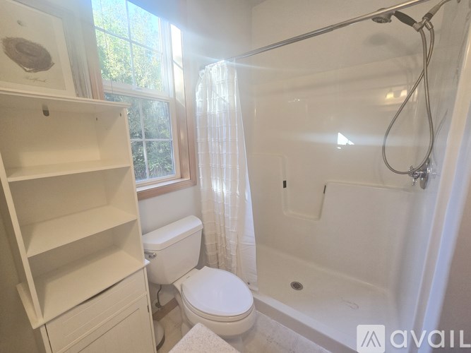A white bathroom with a toilet, a bathtub, and a window.