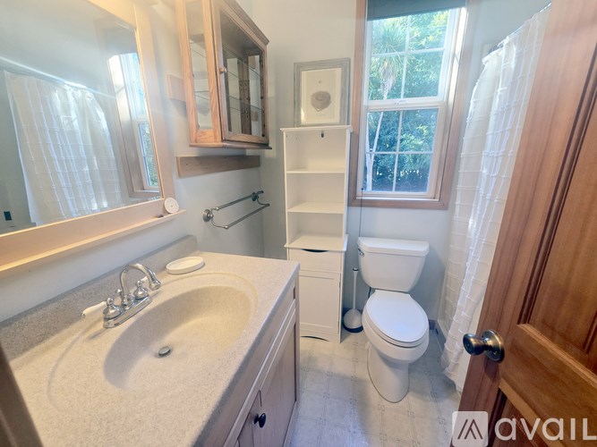 A bathroom with a sink, toilet, and a window.