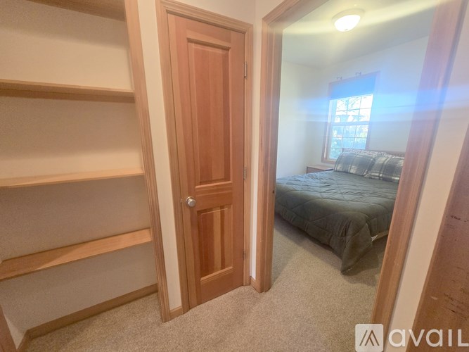 A bedroom with a bed, a window, and a wooden door.