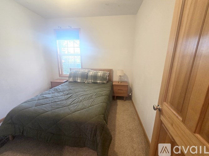 A bedroom with a bed, nightstand, and window.