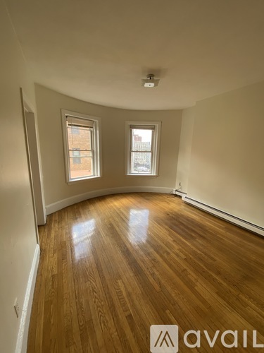 A room with wooden floors and two windows.