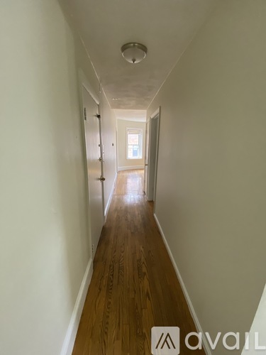 A long hallway with wooden floors and white walls.