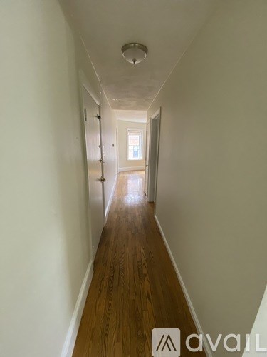 A long hallway with wooden floors and white walls.