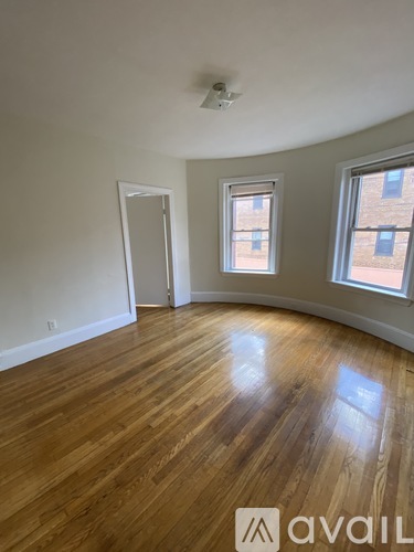 A room with wooden flooring and two windows.