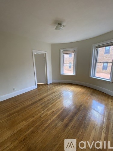 A room with wooden flooring and two windows.