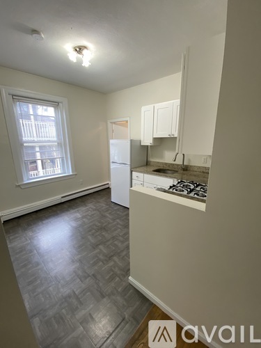 A kitchen with a refrigerator, sink, and cabinets.