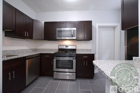 A kitchen with dark brown cabinets and a stainless steel oven.