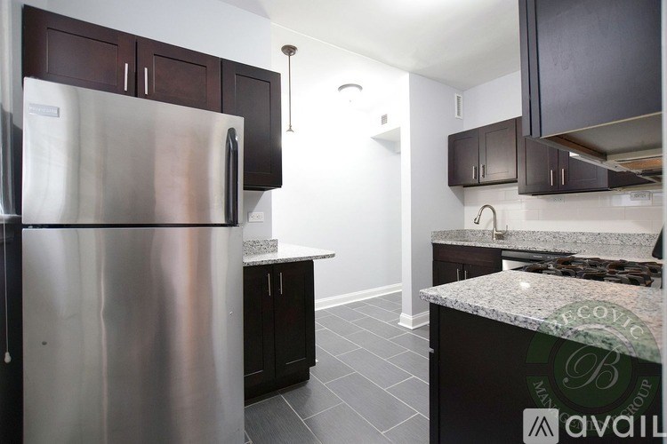 A kitchen with a stainless steel refrigerator and dark brown cabinets.