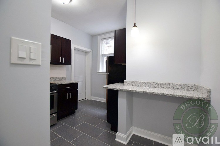 A kitchen with a granite countertop and dark brown cabinets.