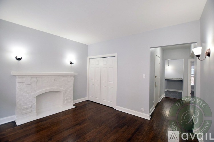 A white fireplace in a room with wood floors and white walls.