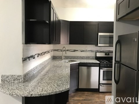 A kitchen with black cabinets and a granite countertop.