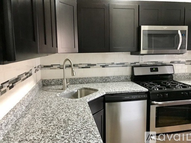 A kitchen with black cabinets and a granite countertop.