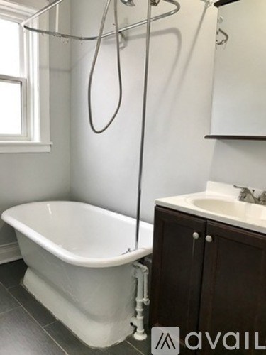 A white bathtub is in a bathroom with a sink and a window.