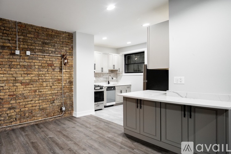 A kitchen with a brick wall and wooden floors.