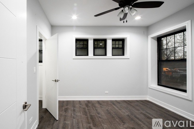 A room with a ceiling fan and three windows.