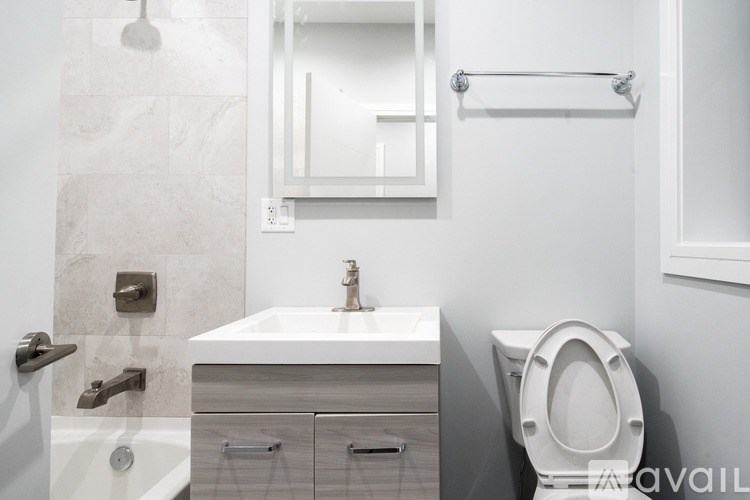 A white bathroom with a toilet, sink, and mirror.