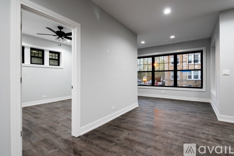 A spacious room with a ceiling fan and large windows.