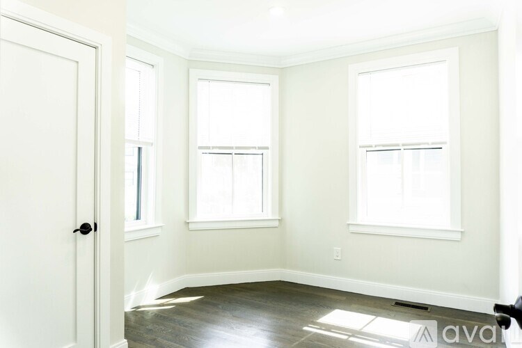 A room with a door, two windows and a wooden floor.