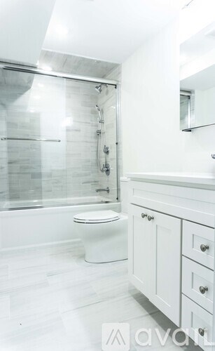 A white toilet in a bathroom with a glass shower door.