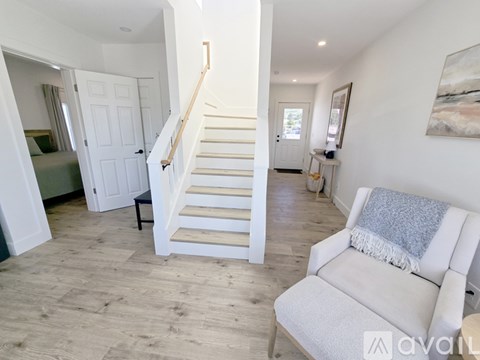 A living room with a white couch and a staircase.