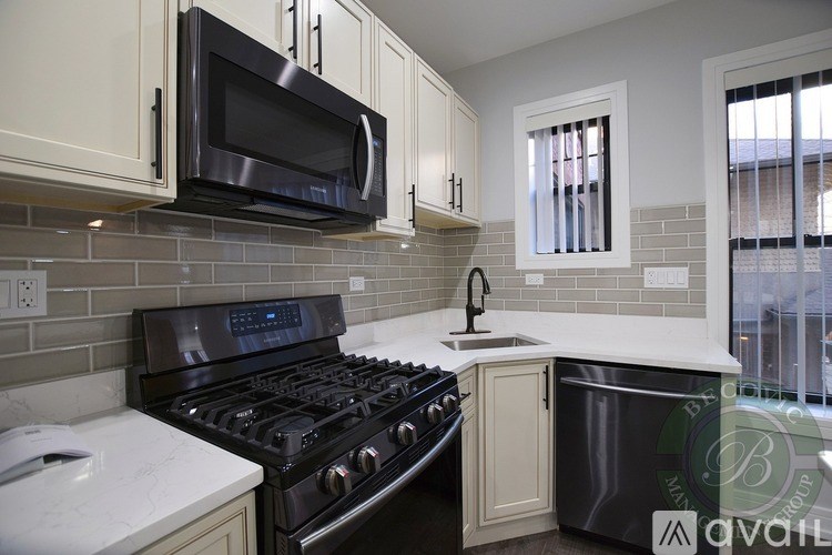 A kitchen with a black stove and microwave above it.