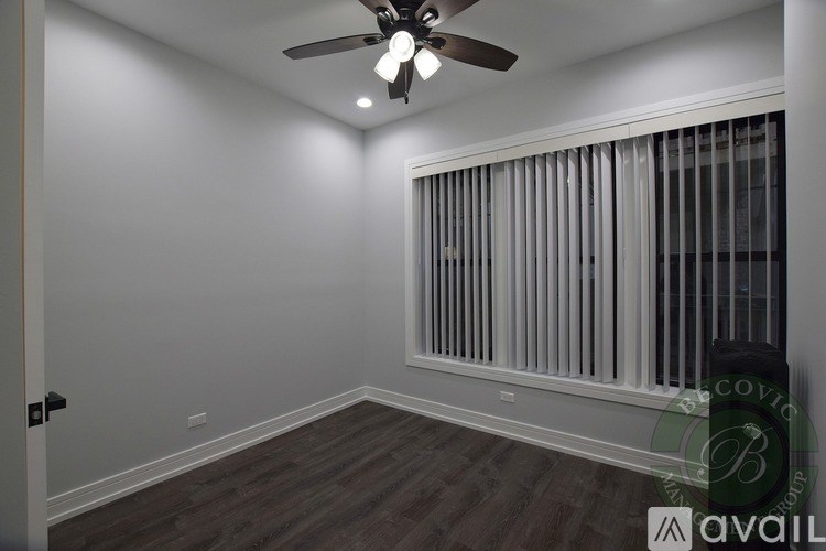 A room with a ceiling fan and a window with blinds.