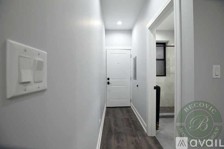 A hallway with a door and a light switch on the wall.