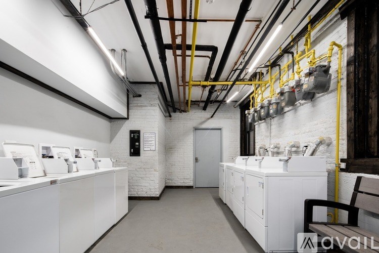 A bathroom with white sinks and yellow pipes.