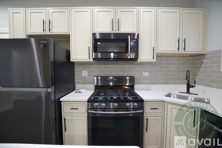A kitchen with a black refrigerator, black oven, and white cabinets.