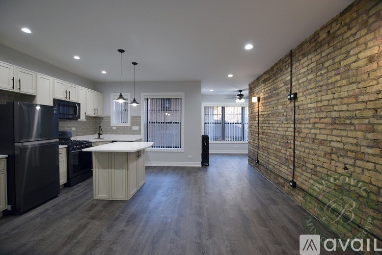 A kitchen with a brick wall and wooden floors.